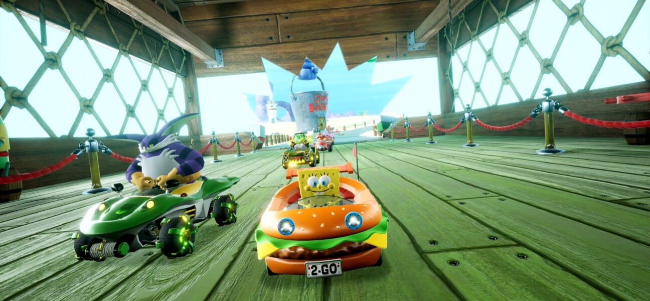 SpongeBob driving the Patty Wagon in a race inside a wooden boardwalk area.