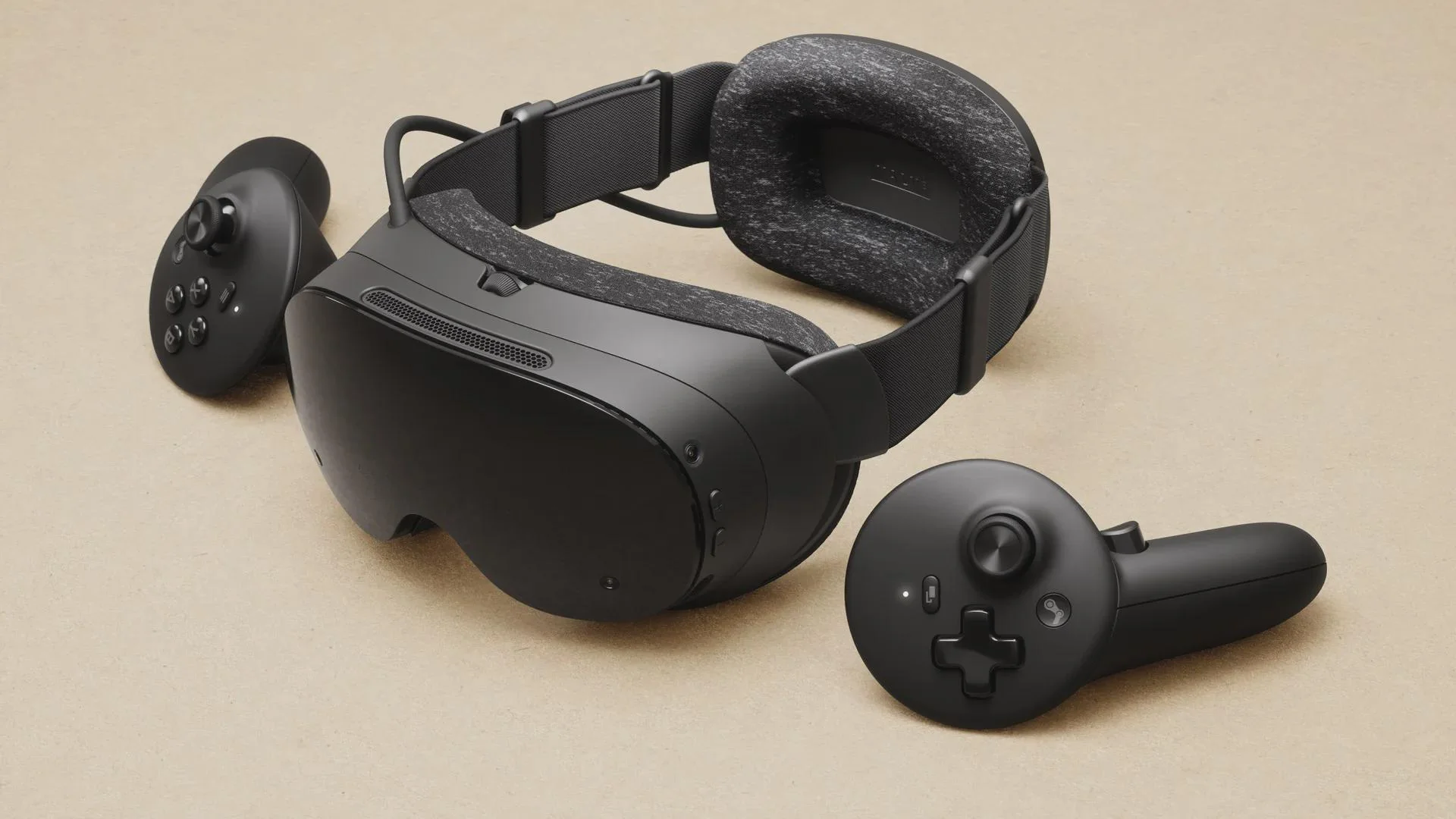 Steam Frame VR headset resting on a flat surface with two matching black controllers beside it.