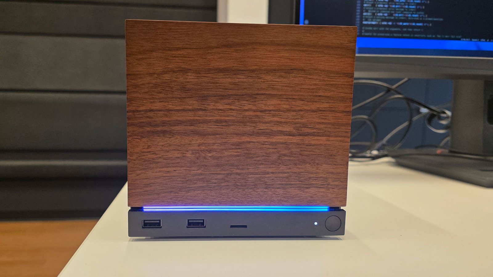 Steam Machine prototype sitting on a desk with a wood front panel, blue LED strip, and front USB ports.